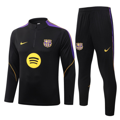 Conjunto desportivo preto com detalhes roxos e amarelos, camisola manga comprida e calças com emblemas FC Barcelona e logos Nike e Spotify.