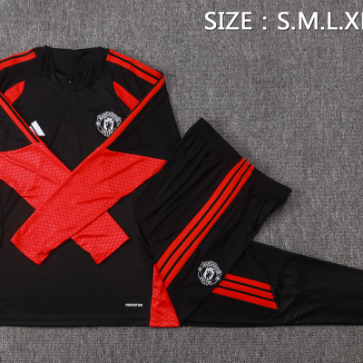 Conjunto desportivo preto e vermelho com emblema Manchester United sobre superfície cinza