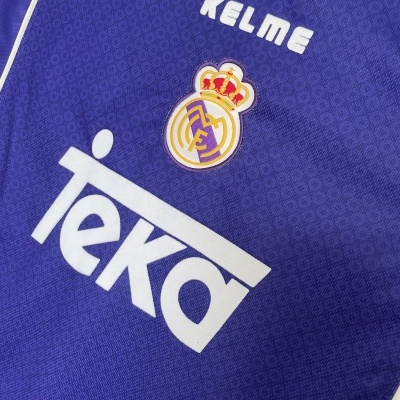 Detalhe de tecido azul com logos e texto KELME e coroa bordada.