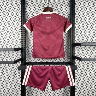 Conjunto desportivo vinho com detalhes brancos pendurado em estrutura metálica preta com fundo de rede metálica