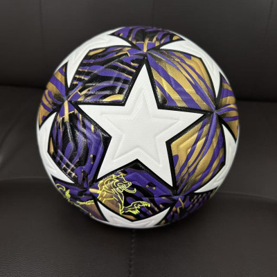 Bola de futebol branca com padrão roxo e dourado em um sofá preto