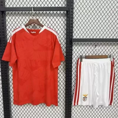 Conjunto de futebol vermelho e branco pendurado numa grade preta