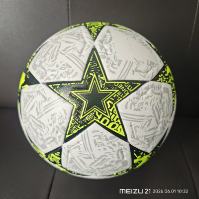 Bola de futebol branca com estrelas pretas e amarelo neon e padrão cinza sobre superfície preta