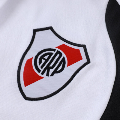 Detalhe de tecido branco e preto com logótipo bordado em escudo ARP vermelho e preto