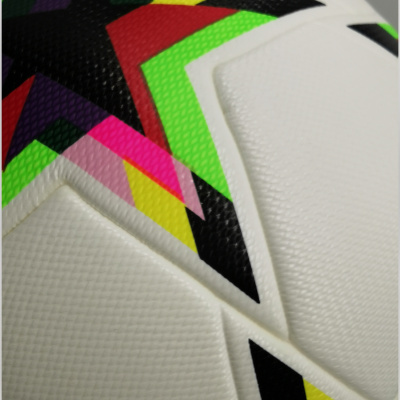 Close-up de bola de futebol branca com padrões geométricos coloridos.