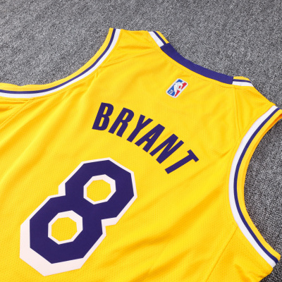 Camisola amarelo-roxa de basquetebol com nome BRYANT e número 8 sobre tapete cinzento