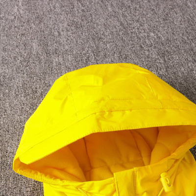 Capuz amarelo de casaco sobre superfície cinzenta texturada