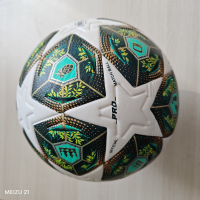 Bola de futebol branca com padrões hexagonais verdes e pretos com detalhes dourados e folhas