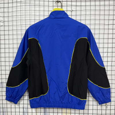 Casaco desportivo azul e preto com linhas amarelas pendurado num cabide