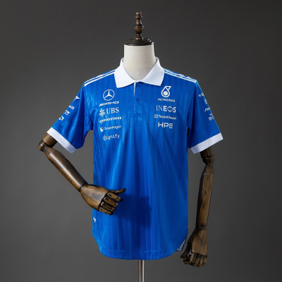 Polo azul com golas brancas e logos variados em branco, apresentado em manequim de madeira.