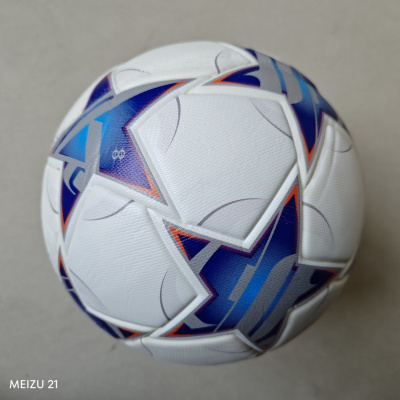 Bola de futebol branca com estampado geométrico colorido sobre fundo cinzento.