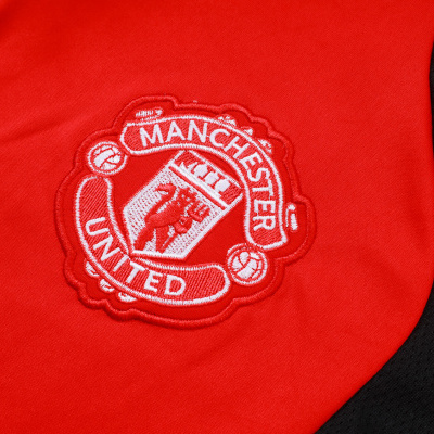 Emblema bordado branco do Manchester United em tecido vermelho e preto.