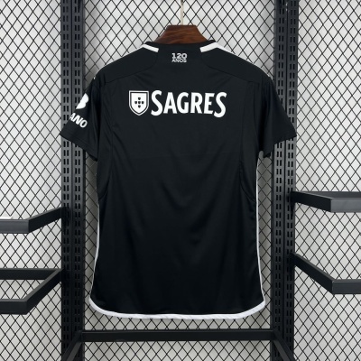 Camisola desportiva preta com logos brancos pendurada em cabide contra parede metálica