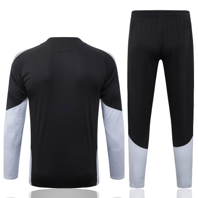 Conjunto de roupa desportiva preta e cinza com camisa de manga comprida e calças.