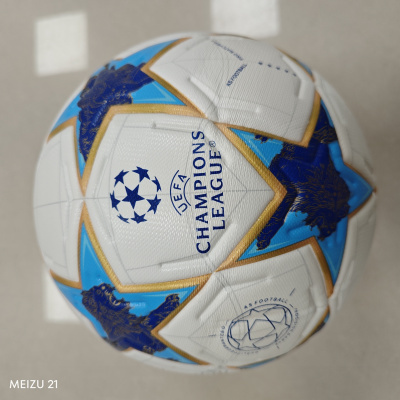 Bola de futebol branca com detalhes em azul e dourado e texto UEFA CHAMPIONS LEAGUE