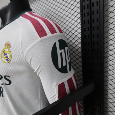 Camisola de futebol branca do Real Madrid com riscas vermelhas nas mangas e logo do clube