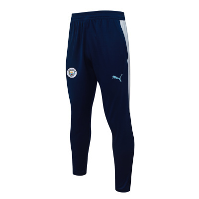 Calças desportivas azuis escuras com listas laterais brancas e logótipos Manchester City e Puma