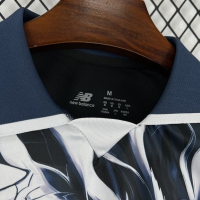 Camisola desportiva New Balance azul e branca com padrão abstrato pendurada num cabide de madeira.