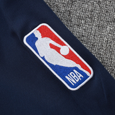 Logótipo bordado da NBA em tecido azul escuro sobre carpete cinzenta.