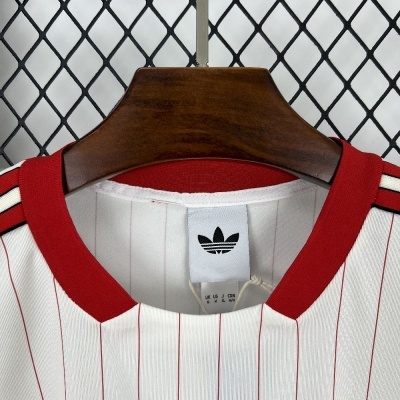 T-shirt branca com riscas vermelhas e gola vermelha em cabide de madeira