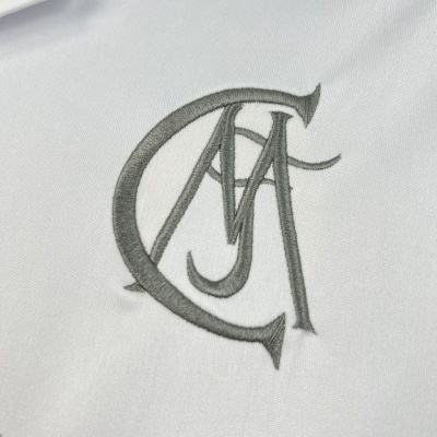 Logótipo bordado em cinzento com letras entrelaçadas CMA sobre tecido branco