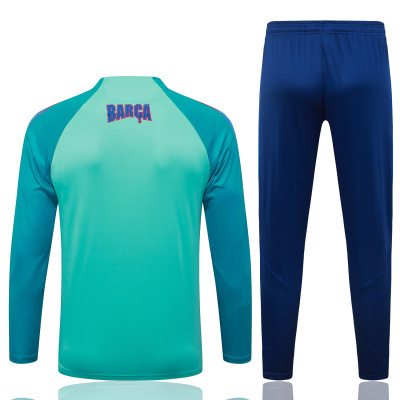 Conjunto desportivo azul turquesa e azul escuro com texto BARÇA nas costas da camisola