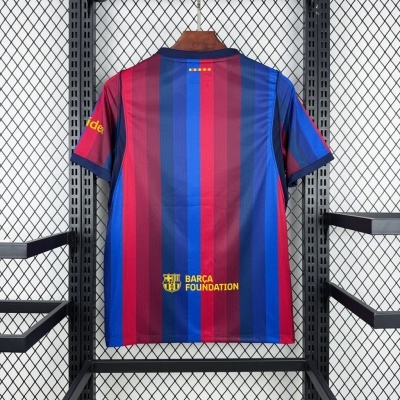 Camisola de futebol com riscas verticais vermelho, azul e burdeos e logo Barca Foundation