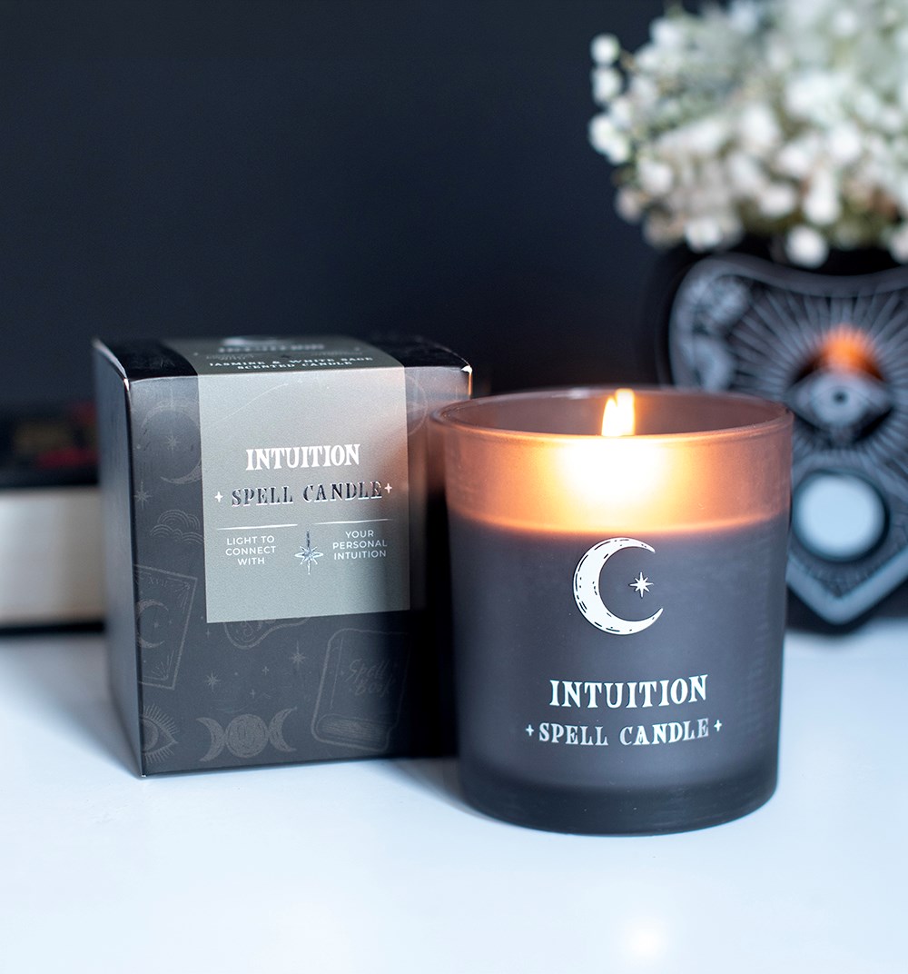 Vela acesa Intuition Spell Candle em vidro cinzento com caixa preta ao lado