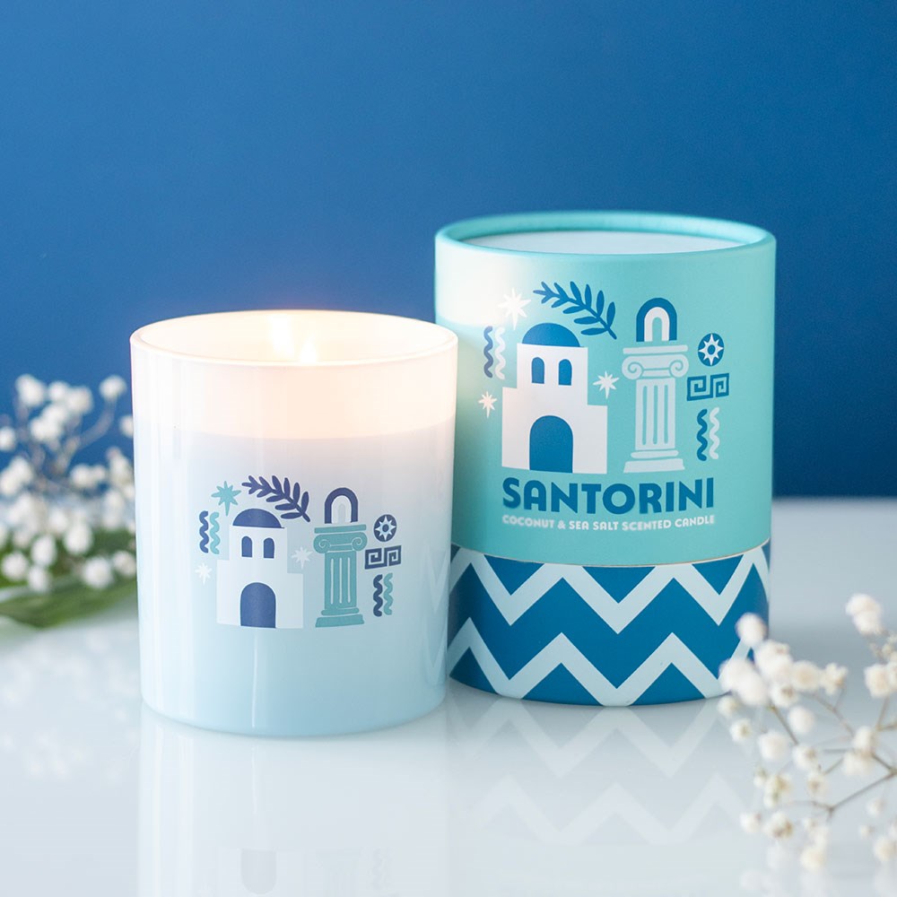 Vela perfumada com embalagem azul claro e branca com ilustração e texto SANTORINI