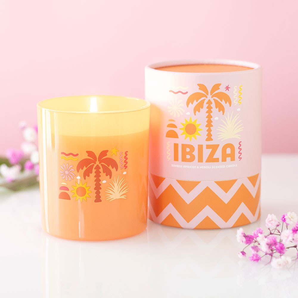 Vela perfumada laranja e embalagem com design tropical e texto IBIZA