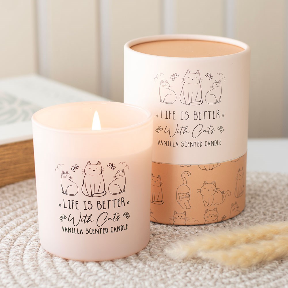 Vela perfumada de baunilha com desenho de gatos e texto em recipiente rosa claro e embalagem cilíndrica