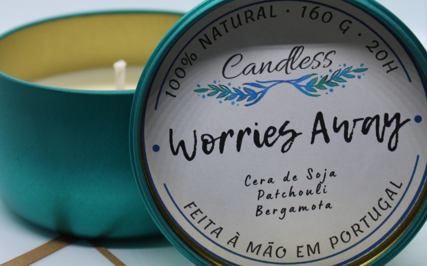 Vela em lata verde com tampa rotulada com texto sobre composição e origem.