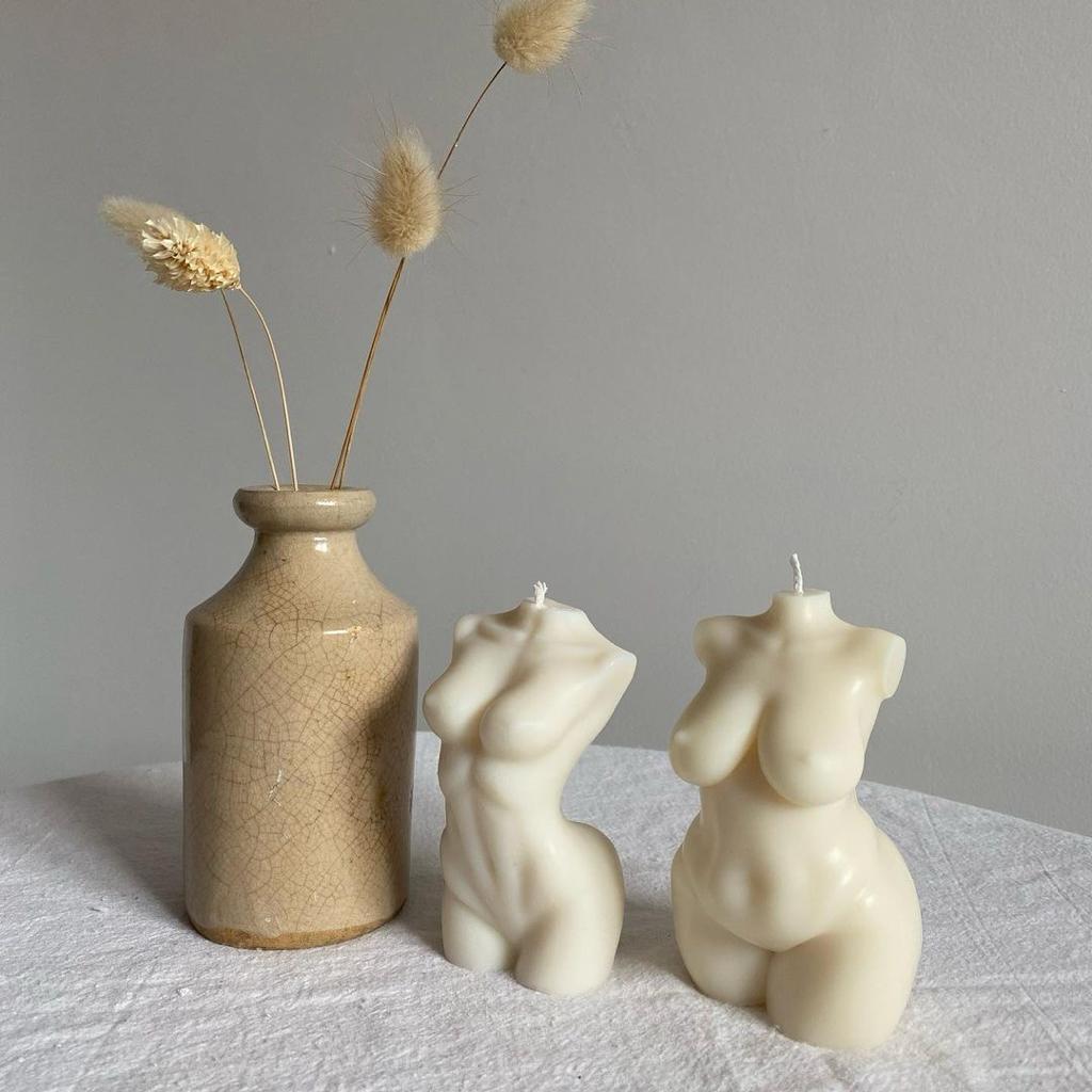 Dupla de Velas Aromáticas Corpo Vaso cerâmico bege com ramos secos e duas velas em forma de torso feminino creme.
