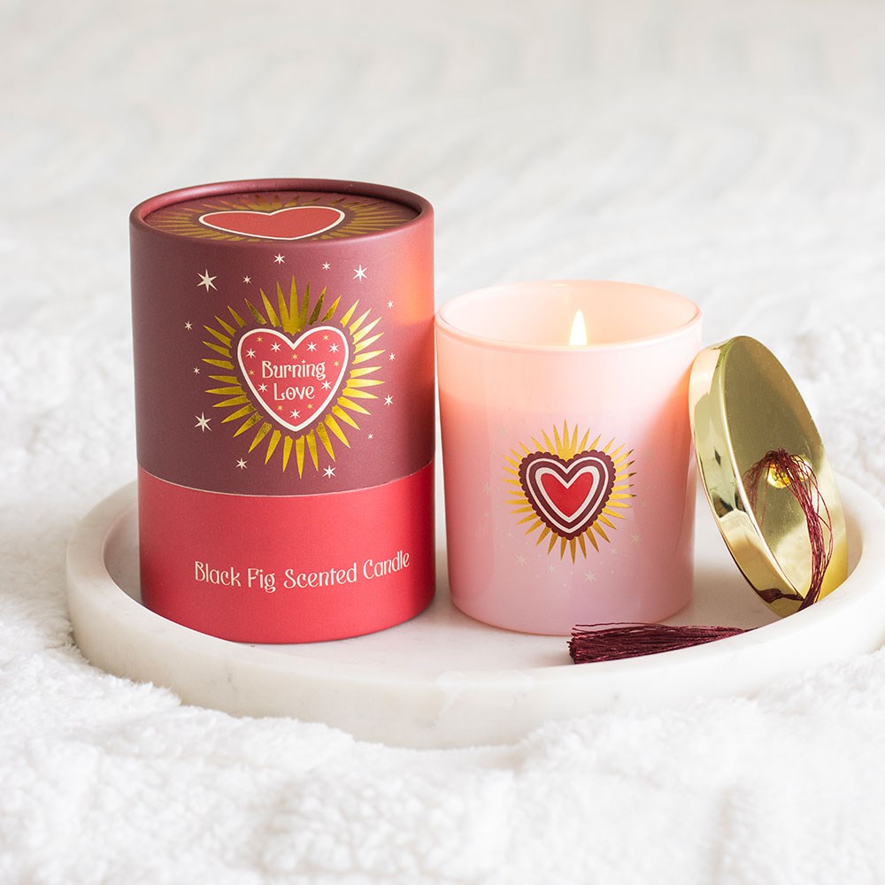 Vela perfumada Black Fig em copo de vidro rosa claro com tampa dourada e embalagem vermelha com design de coração