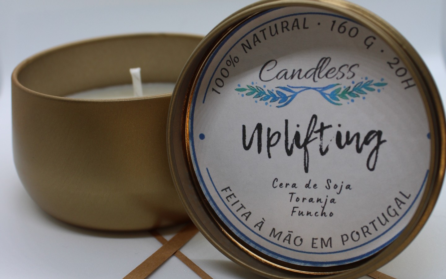 Vela em recipiente metálico dourado com tampa com etiqueta branca