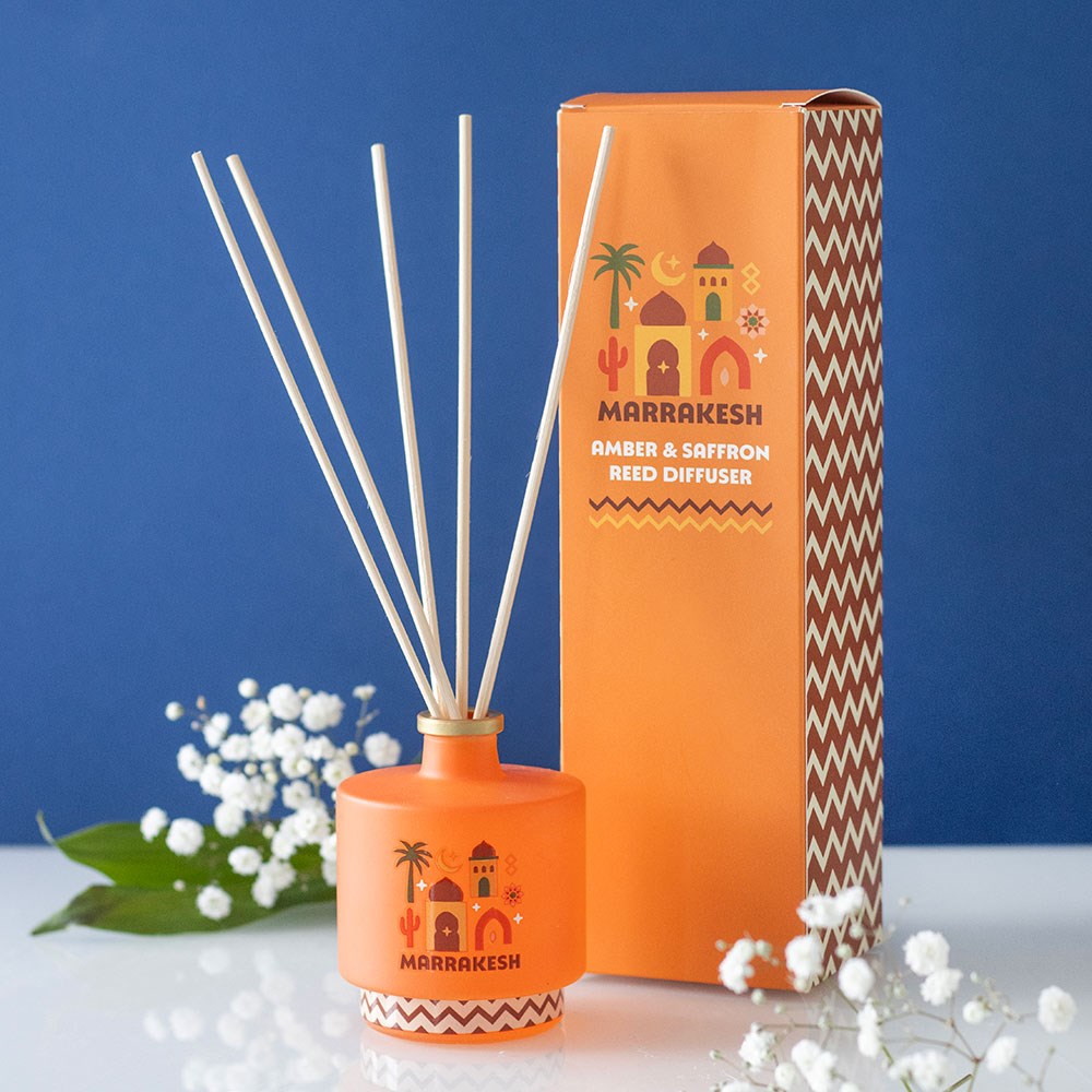 Difusor de Varetas Marrakesh Amber & Saffron Difusor de varetas aromático laranja com design Marrakesh ao lado de sua caixa correspondente