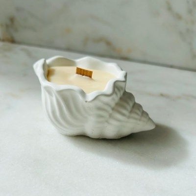 Vela em recipiente cerâmico branco em forma de concha com pavio de madeira