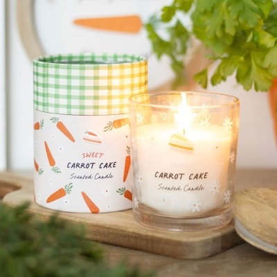 Vela perfumada com aroma de bolo de cenoura em copo de vidro com embalagem decorada com cenouras e bolos.
