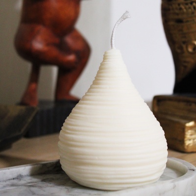 Vela branca em forma de gota com textura em espiral sobre prato de mármore