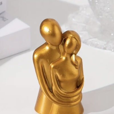 Escultura dourada de casal abraçado minimalista