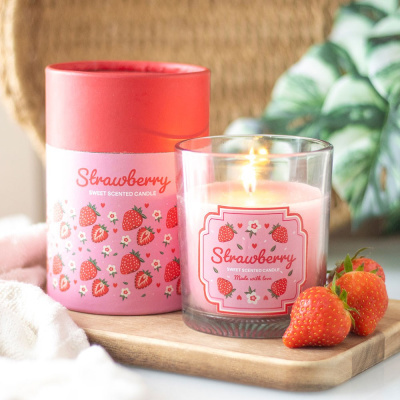 Vela perfumada de morango em copo de vidro com embalagem rosa e morangos frescos