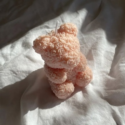 Urso feito de pequenas flores cor-de-rosa sobre tecido branco