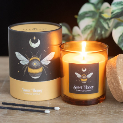 Vela perfumada Sweet Honey com embalagem e fósforos sobre madeira