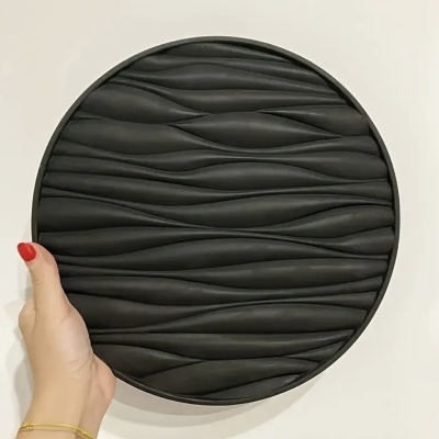 Placa decorativa circular preta com texturas onduladas