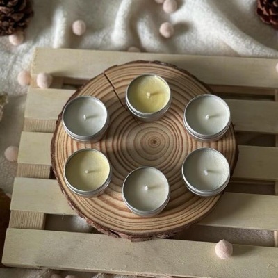 Seis velas em recipientes metálicos sobre base de madeira redonda