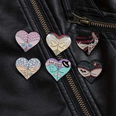 Seis pins em forma de coração com desenhos variados sobre tecido preto com zíperes