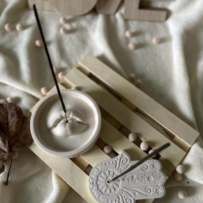 Castiçais de incenso branco com pau de incenso sobre tábua de madeira clara e fundo com letras decorativas LOVE