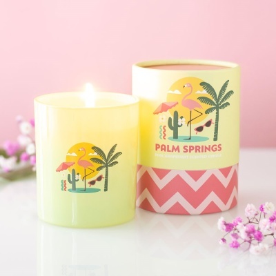 Vela aromática rosa com embalagem amarela e rosa, decoração tropical e texto PALM SPRINGS.