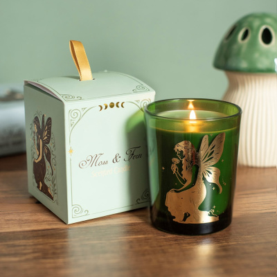 Vela verde perfumada com desenho dourado de fada e caixa decorativa branca