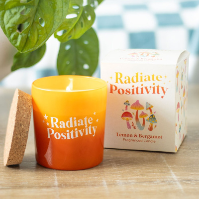 Vela de vidro laranja Radiate Positivity com tampa de cortiça e embalagem branca com ilustrações coloridas